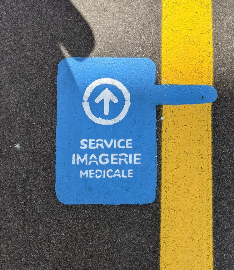 Signalétique au sol dans un hôpital, avec une ligne jaune guidant les patients vers le service d'imagerie médicale, assurant un chemin clair et sécurisé à suivre.