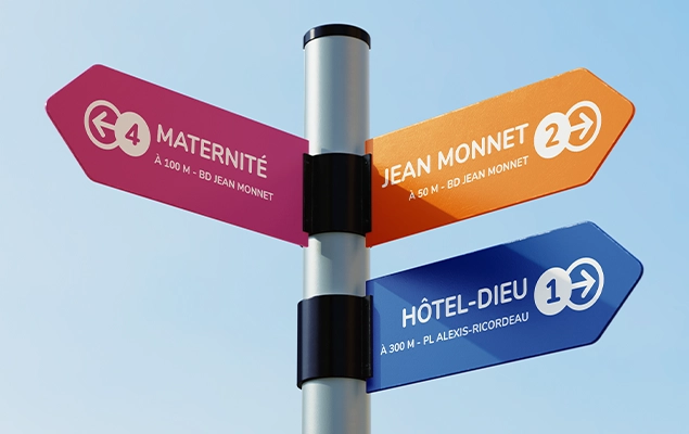 Signalétique directionnelle dans un hôpital, avec des panneaux clairs indiquant les directions vers les différentes zones et des portes numérotées pour faciliter l'orientation des patients.